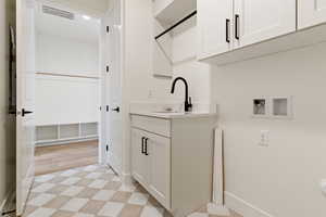Laundry room with hookup for a washing machine, cabinet space, light floors, and baseboards