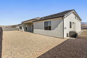 Rear view of property with a fenced backyard, central AC, stucco siding, and a patio area
