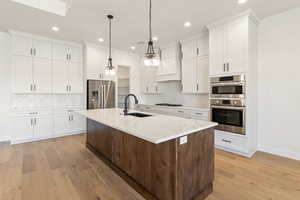 Kitchen featuring stainless steel appliances, a sink, recessed lighting, light wood finished floors, and tasteful backsplash