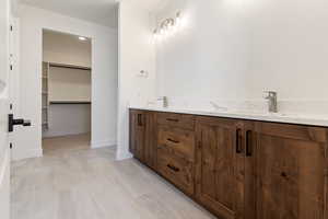 Full bath with a walk in closet, a sink, marble finish floors, and baseboards