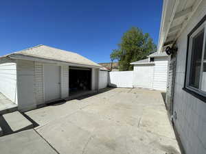 View of patio / terrace featuring an outbuilding, fence, and a garage