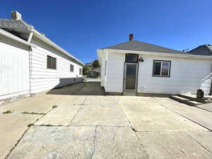 Back of house featuring a patio, a chimney, and a shingled roof