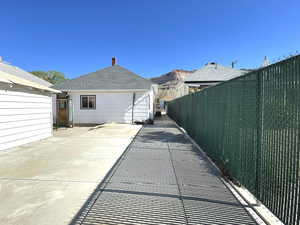Rear view of property with fence, a patio, and a shingled roof