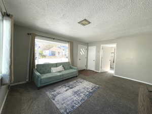 Living area with carpet floors, a textured ceiling, and baseboards
