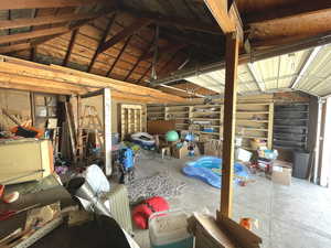 Misc room with lofted ceiling, a garage, and unfinished concrete flooring