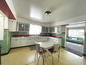 Kitchen with a sink, stainless steel countertops, and white cabinets