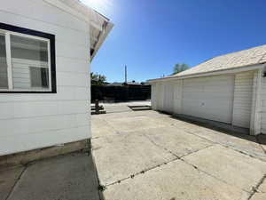 View of property exterior with a patio, fence, and an outdoor structure