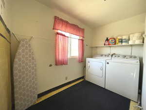 Clothes washing area featuring washer and clothes dryer and baseboards