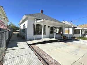 Back of property with a gate, a shingled roof, covered porch, fence, and a chimney