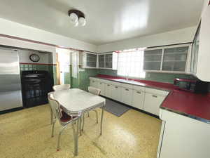 Kitchen featuring black appliances, white cabinets, a sink, dark countertops, and tasteful backsplash
