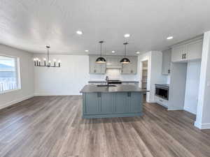 Kitchen with stainless steel microwave, gray cabinetry, a textured ceiling, a chandelier, and dark countertops