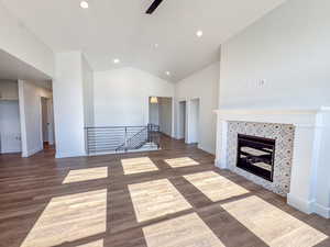 Unfurnished living room with vaulted ceiling, wood finished floors, recessed lighting, and a tile fireplace