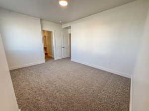 Carpeted spare room featuring baseboards