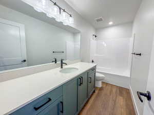 Bathroom featuring wood finished floors, vanity, tub / shower combination, and recessed lighting