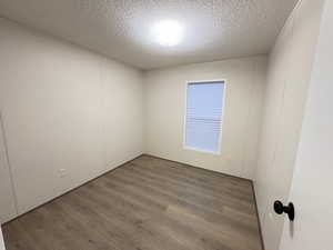 Empty room featuring wood finished floors and a textured ceiling