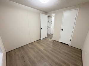 Unfurnished bedroom with wood finished floors and a textured ceiling