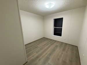 Empty room with a textured ceiling and wood finished floors