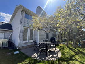 Back of house with a patio, a lawn, and a chimney