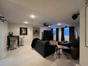 Living area featuring a textured ceiling, baseboards, ceiling fan, carpet flooring, and recessed lighting