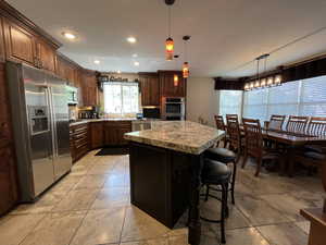Kitchen with stainless steel appliances, a sink, a center island, decorative light fixtures, and recessed lighting