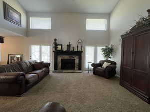 Living area with a high ceiling, carpet floors, a fireplace, and plenty of natural light