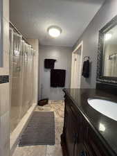 Bathroom with a shower with shower curtain, vanity, and a textured ceiling