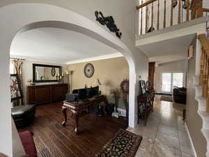 Foyer entrance featuring arched walkways, ornamental molding, a textured ceiling, and baseboards