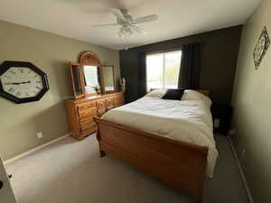 Bedroom featuring light carpet, baseboards, and ceiling fan