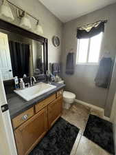 Bathroom with toilet, vanity, a shower with curtain, and baseboards