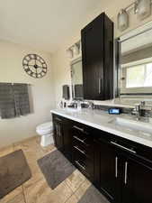 Full bath with double vanity, toilet, and tile patterned flooring
