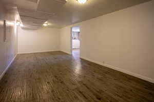 Finished below grade area with washer / dryer, dark wood-style floors, baseboards, and electric panel