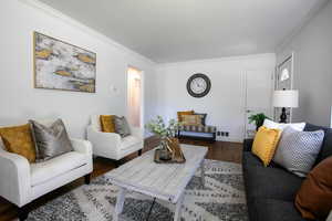 Living room featuring ornamental molding, hardwood floors, and baseboards