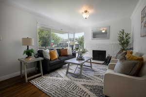 Living area with hardwood floors, a brick fireplace, crown molding, and baseboards