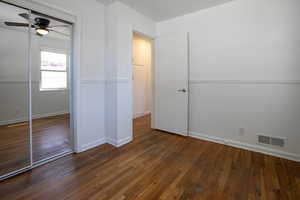 Unfurnished bedroom featuring a closet, wood finished floors, baseboards, and ceiling fan