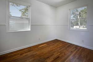 Spare room featuring dark wood finished floors, healthy amount of natural light, and baseboards
