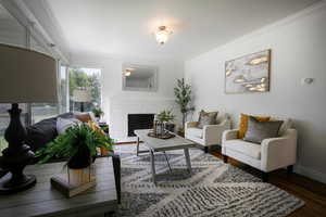 Living room featuring ornamental molding, hardwood floors, a fireplace, and baseboards