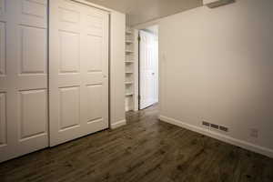 Unfurnished bedroom with dark wood finished floors and baseboards