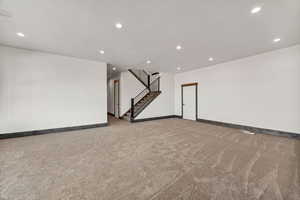 Basement with recessed lighting, light colored carpet, and stairway