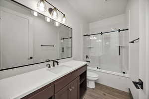 Bathroom with vanity, bath / shower combo with glass door, and light wood-style flooring