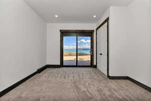 Empty room featuring a water view, light colored carpet, and recessed lighting