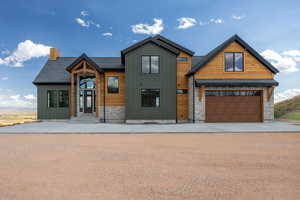 View of front of house featuring board and batten siding, stone siding, a chimney, and concrete driveway