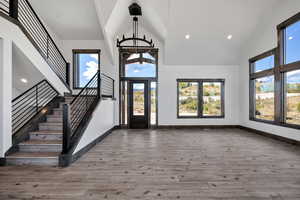 Foyer entrance with recessed lighting, high vaulted ceiling, stairway, light wood-style floors, and a chandelier