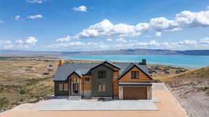View of front of property with stone siding, driveway, a garage, a water and mountain view, and roof with shingles