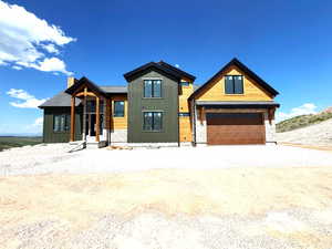 View of front of property with stone siding, a chimney, and driveway