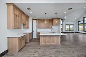 Kitchen with a center island with sink, decorative light fixtures, recessed lighting, light wood finished floors, and lofted ceiling