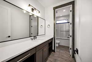 Full bath with shower / bath combination with glass door, vanity, light wood finished floors, and recessed lighting