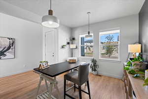 Dining space featuring light wood-style floors, and a textured ceiling