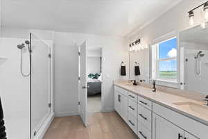 Primary bathroom suite featuring a shower stall, double vanity