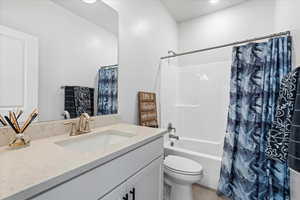 Bathroom with vanity, shower / bath combination with curtain, and toilet