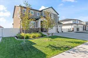 View of front facade featuring board and batten siding, driveway, a gate, a garage, and stone siding
